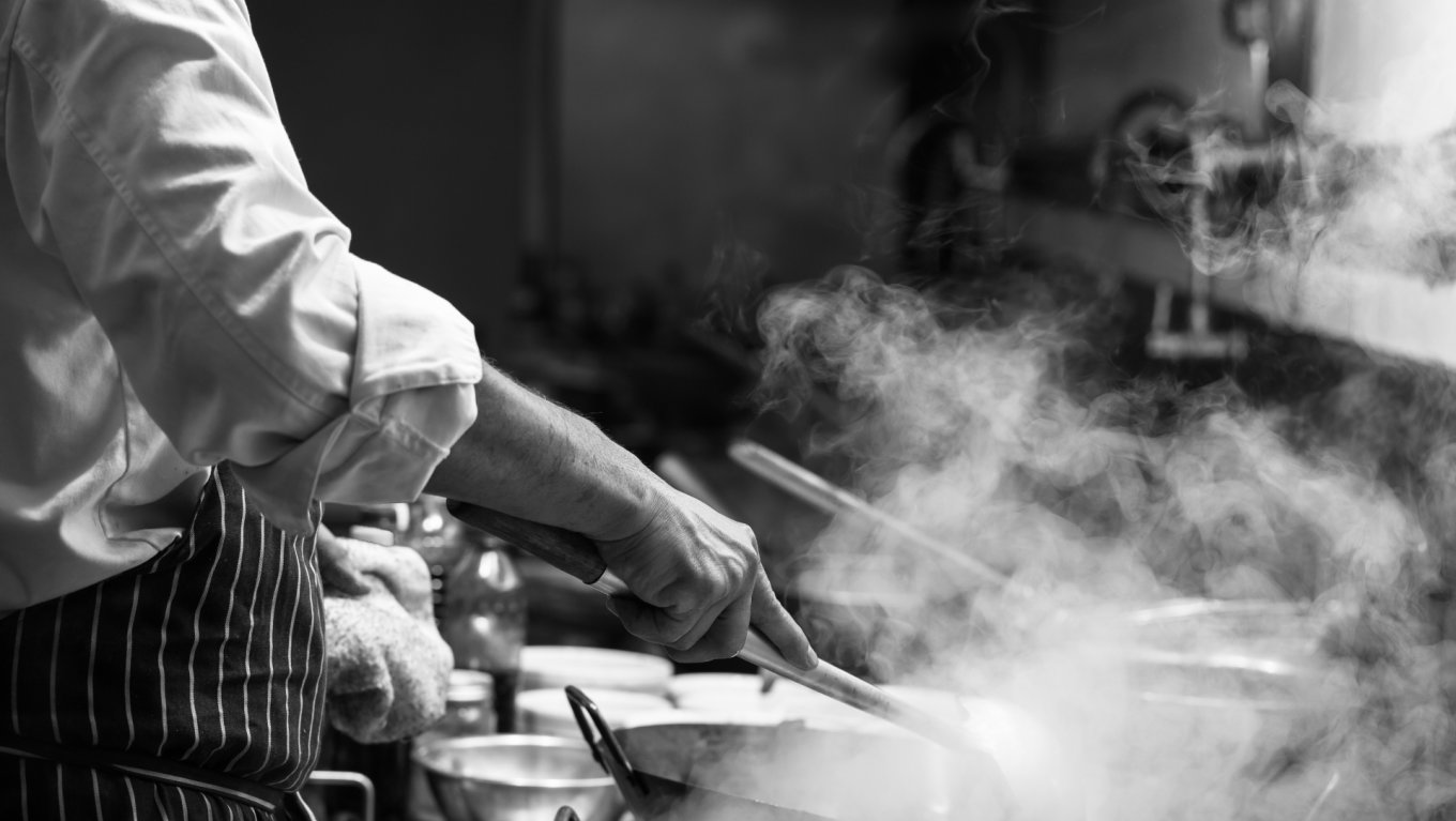 Chef is stirring vegetables in wok,monochrome